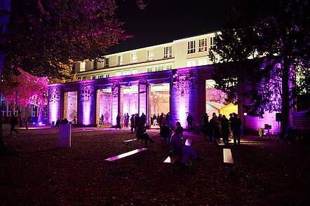 Foto: Blick auf das Hochschulgebäude der Universität der Künste Berlin, das bei Nacht bunt illuminiert ist.