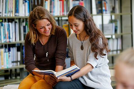 Studentinnen in der Bibliothek (Foto: Thomas Berg / Universität zu Lübeck) Foto: Zwei Studentinnen sitzen in der Bibliothek und lesen in einem Buch.
