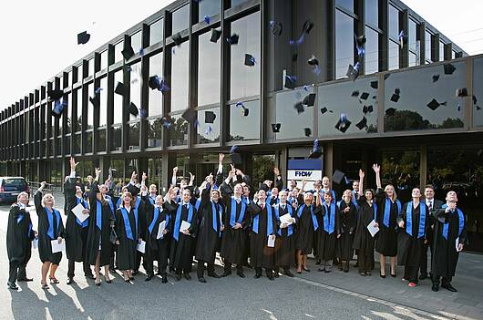 Foto: Absolventinnen und Absolventen werfen während der Abschlussfeier ihre Hüte