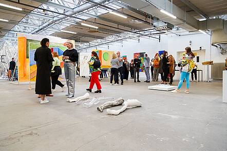 Foto: Besucherinnen und Besucher einer Ausstellung unterhalten sich über die Kunstwerke