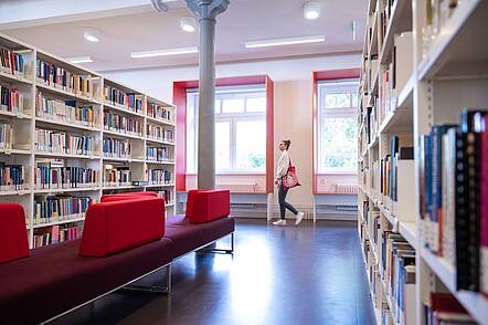 Foto: Eine Studentin geht durch die Bibliothek der Universität Hamburg.