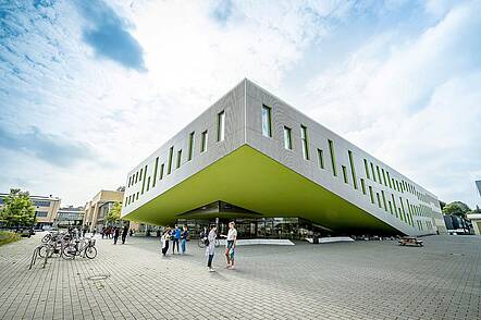 Foto: Blick auf das moderne SL-Gebäude am Campus Westerberg mit Studierenden im Vordergrund