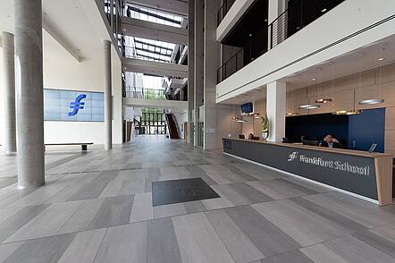 Foto: Blick in das lichtdurchflutete Foyer der Frankfurt School of Finance & Management mit langem Empfangscounter auf der rechten Seite
