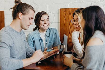 Foto: Studierende der DHAW besprechen sich am Tisch.