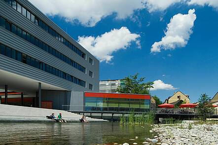 Foto: Gebäude der Hochschule Augsburg mit See im Vordergrund und Mensa im Hintergrund